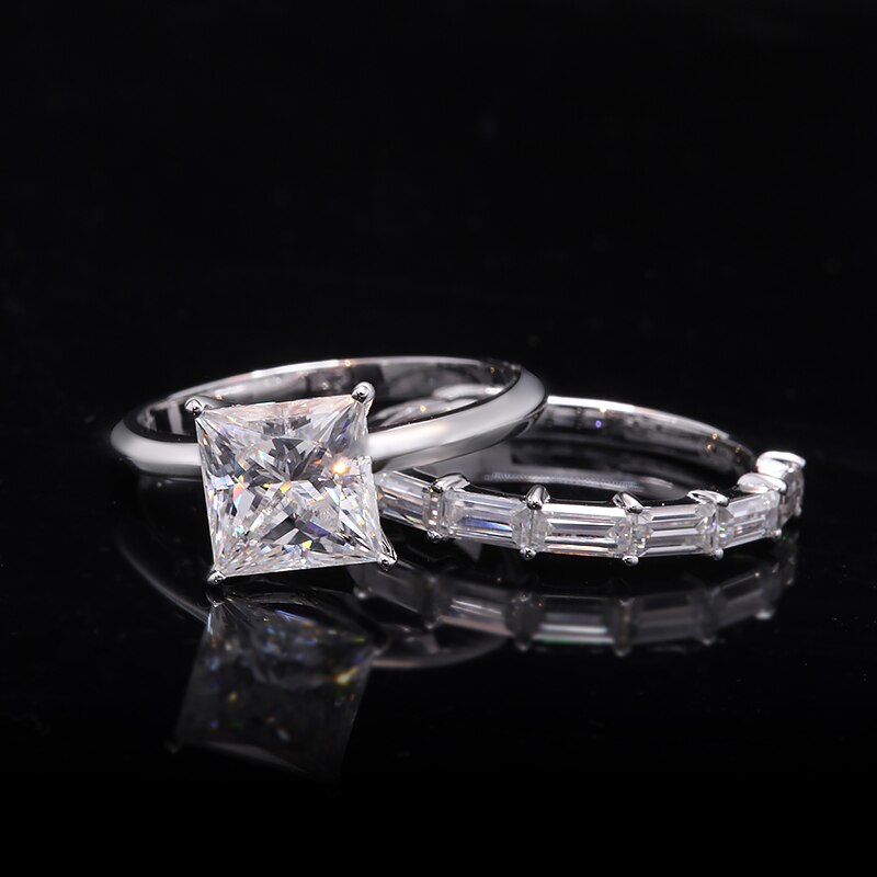 A silver ring set with a 2CT princess cut moissanite and paired with a moissanite baguette half eternity wedding band.
