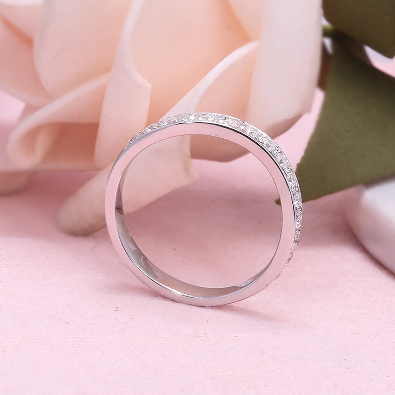 A silver curved wedding band with moissanites along the band.