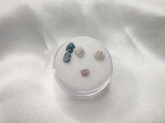 Two blue, two white and one pink raw diamond chunks.