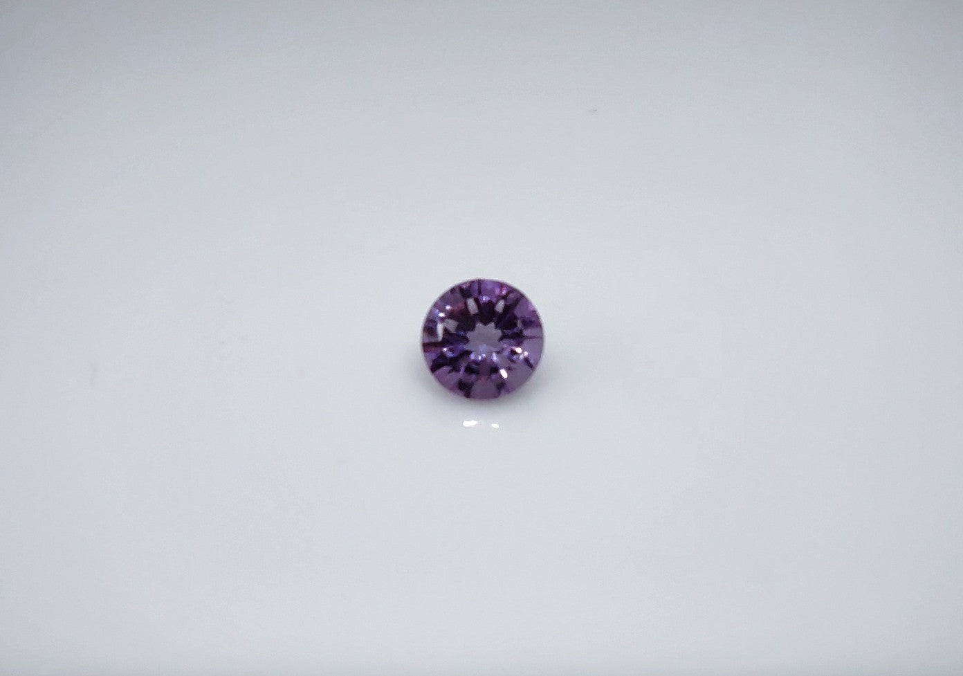 A round illusion cut dark purple amethyst.