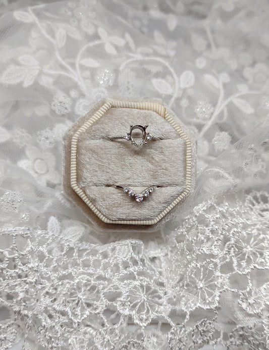 A silver pear cut semi mount with a matching chevron wedding band.