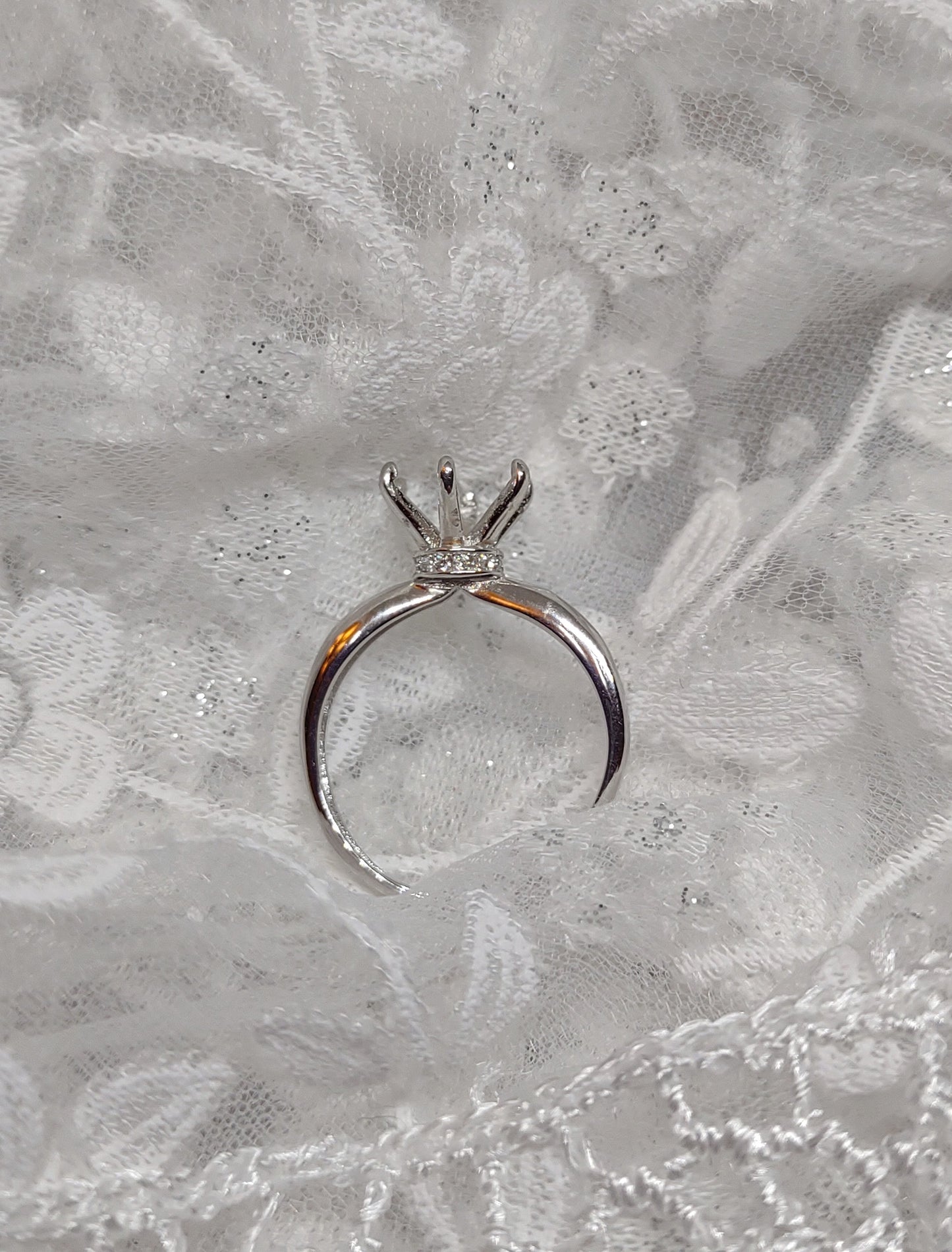 A silver solitaire semi mount with a gem encrusted collar detail.
