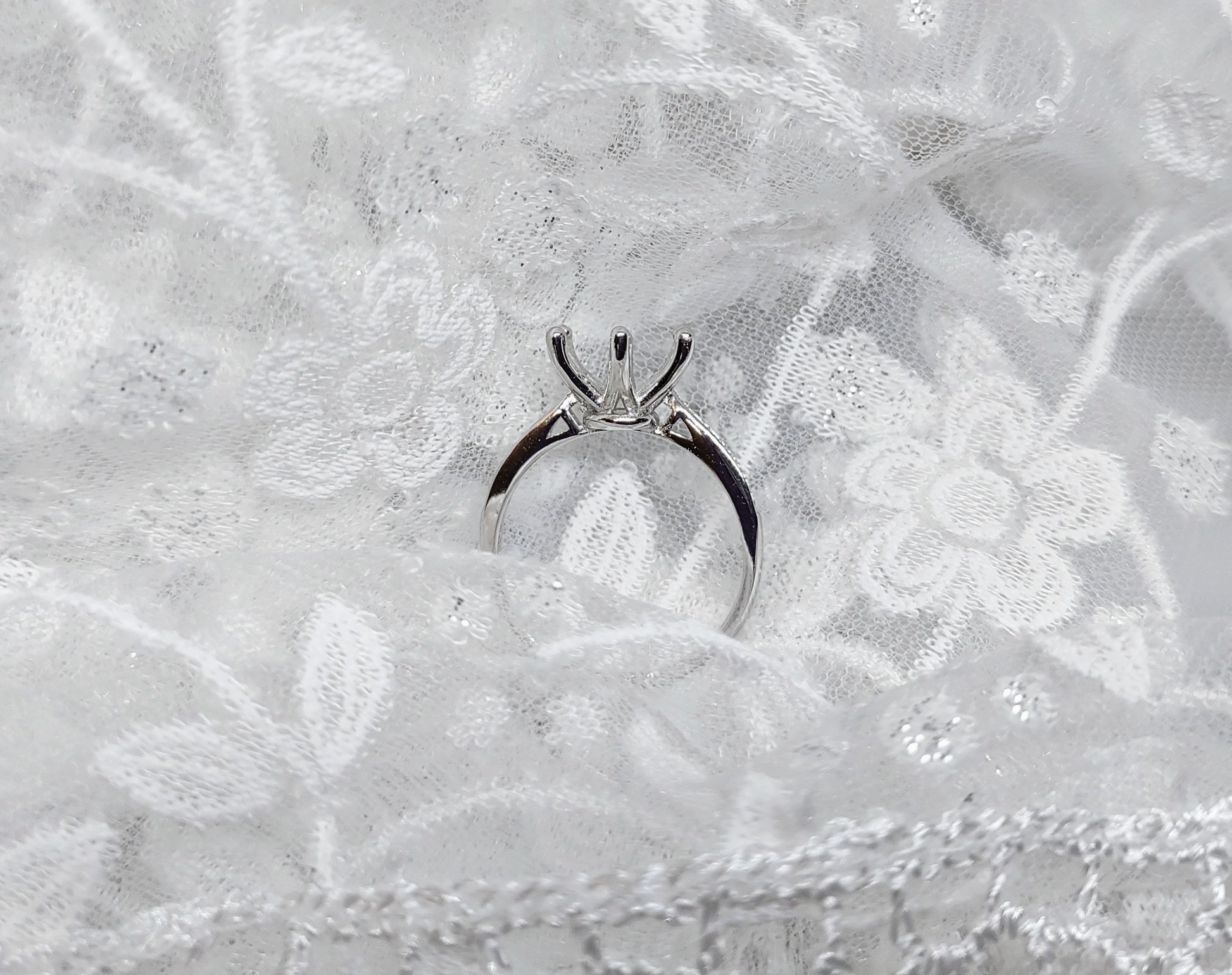 A silver solitaire semi mount with pave band.