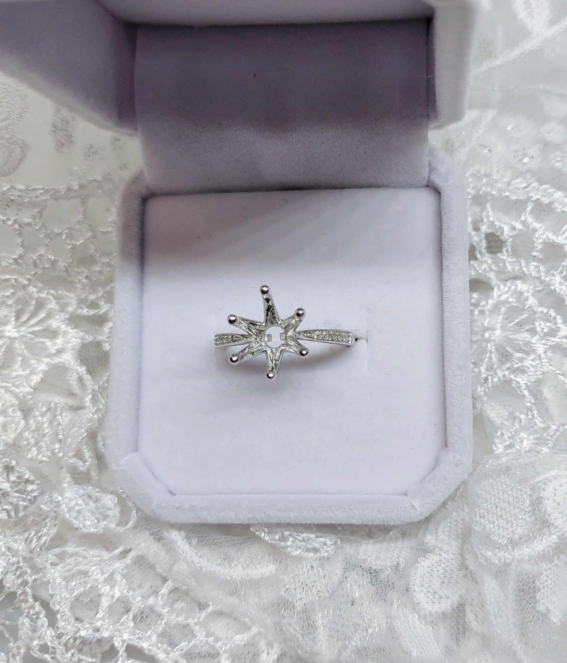 A silver solitaire semi mount with pave band.