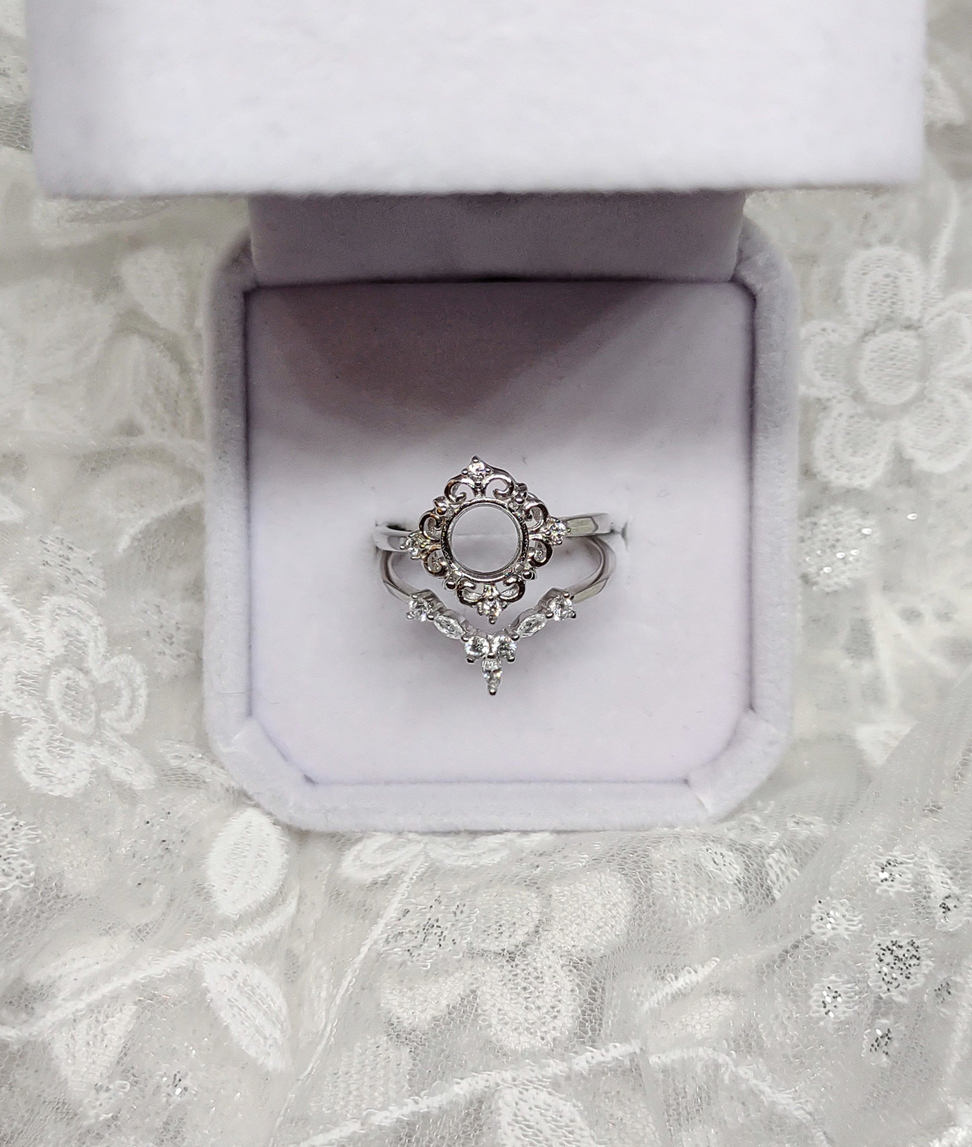 A silver halo semi mount with a diamond shape and 4 small clear gems on the top, bottom and on each side.