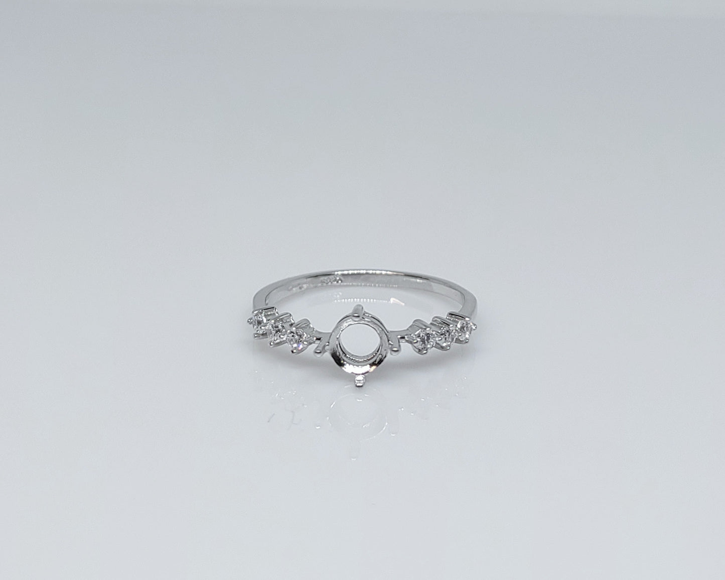 A silver semi mount with tiny round clear gems on both sides.