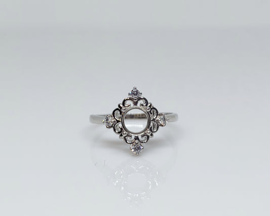 A silver halo semi mount with a diamond shape and 4 small clear gems on the top, bottom and on each side.