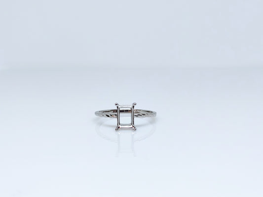 A silver semi mount with a twisted band and needing to be set with a emerald cut gem.