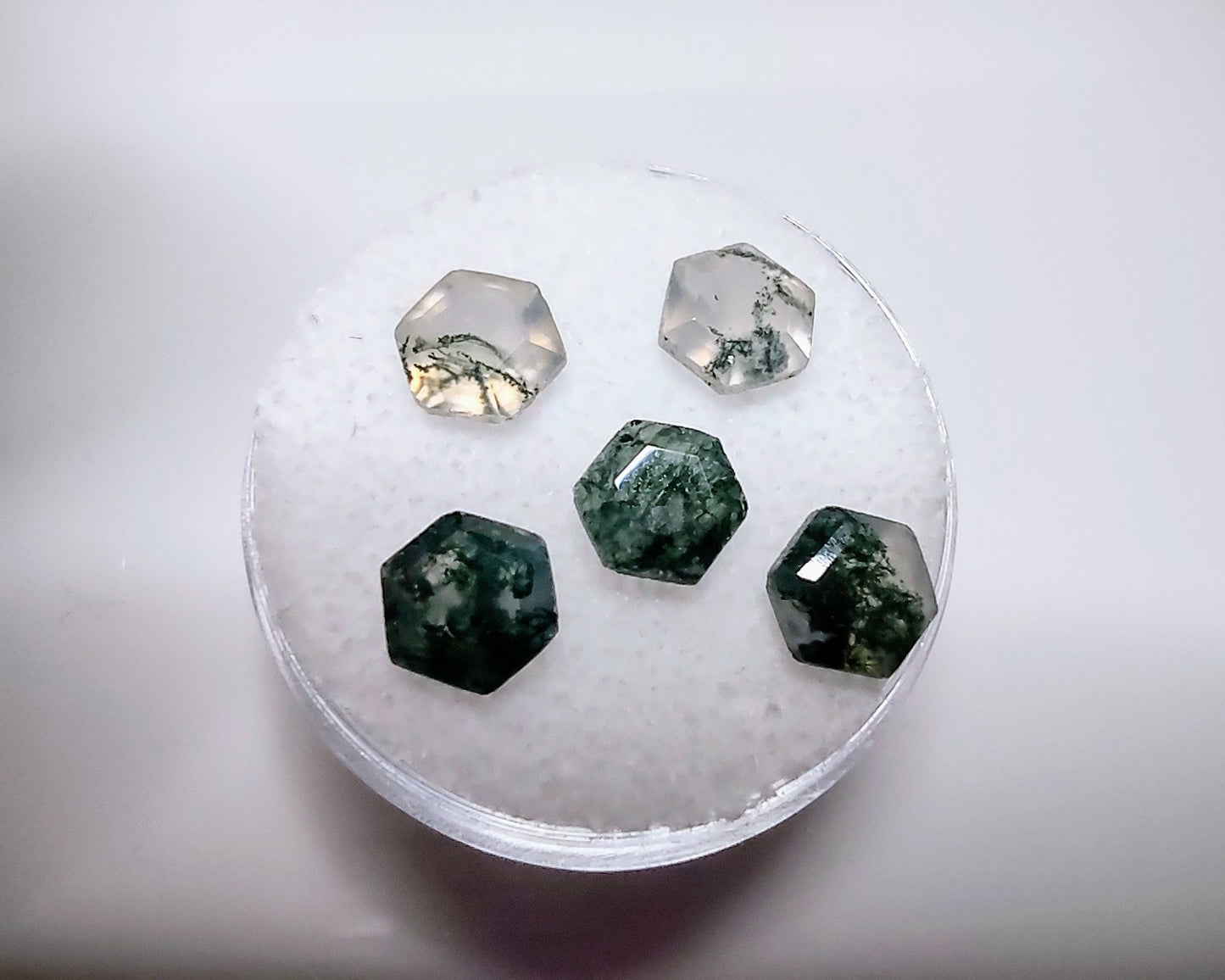 5 hexagon cut moss agate gems with varying intensities of green.