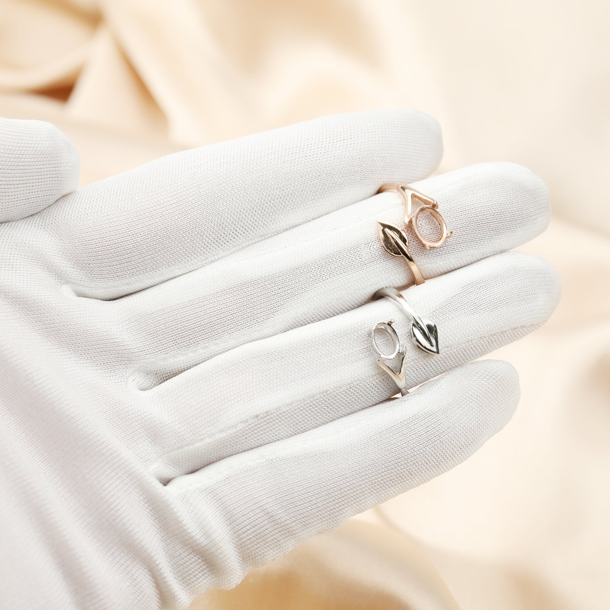 A hand wearing a silver and a rose gold wrap around style oval semi mount with a silver leaf at the other end.