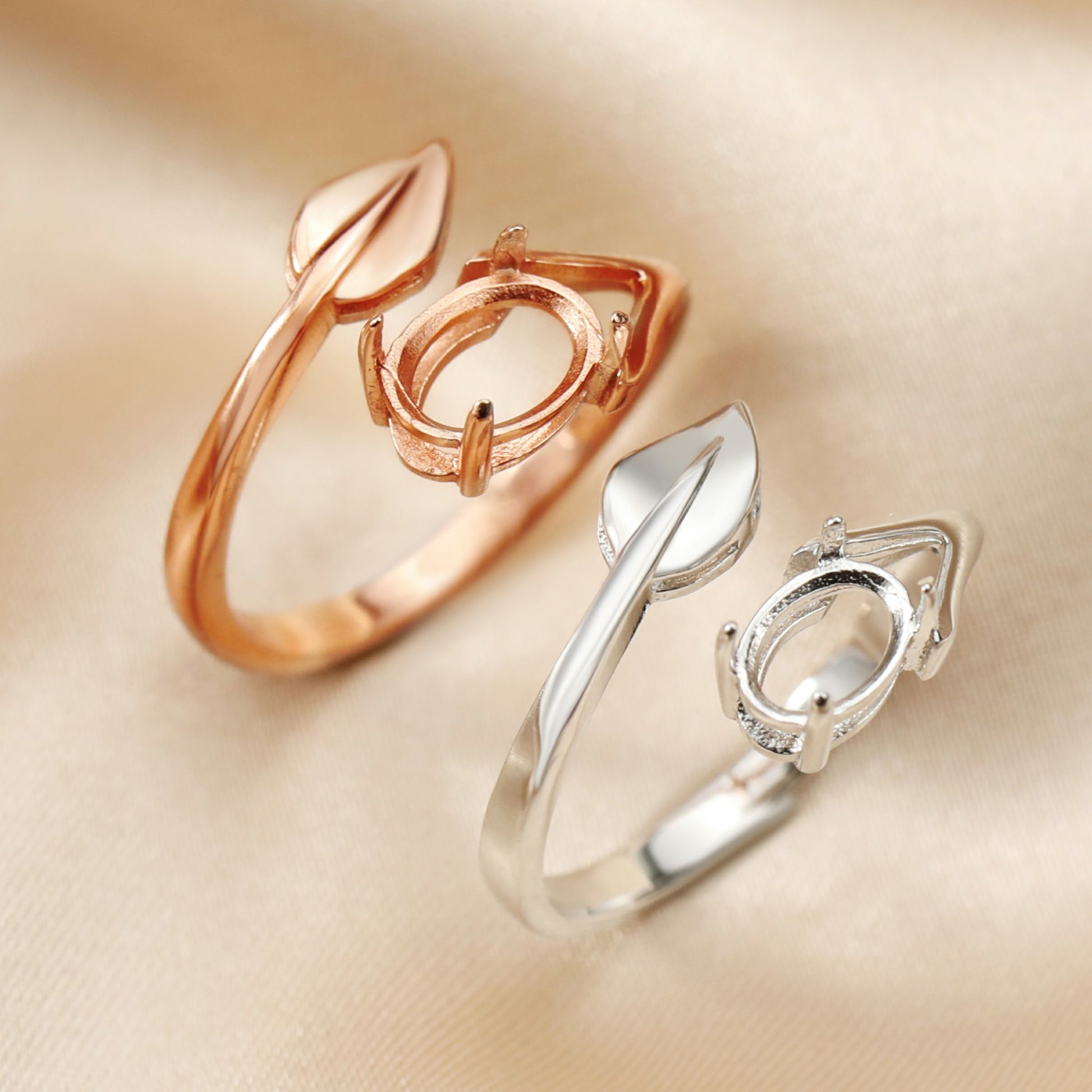 A silver and a rose gold wrap around style oval semi mount with a silver leaf at the other end.