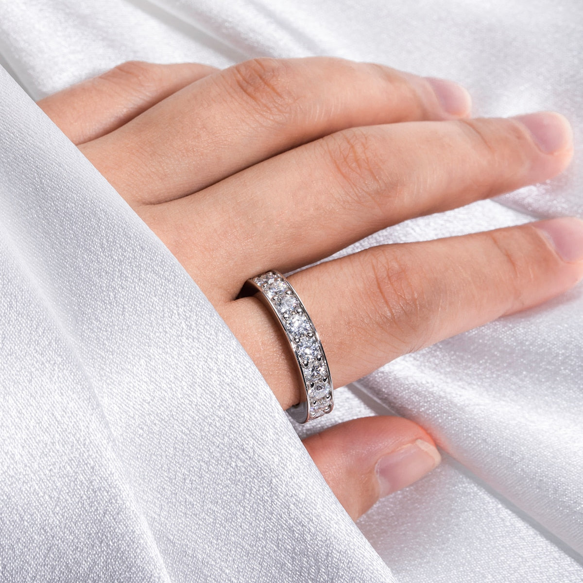 A hand wearing a silver full infinity ring set with 3.5mm moissanites.