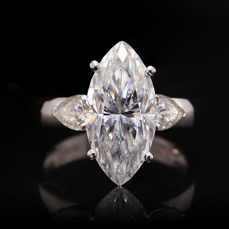 Solid white gold marquise cut moissanite 3 stone engagement ring with tear drop accents on each side.