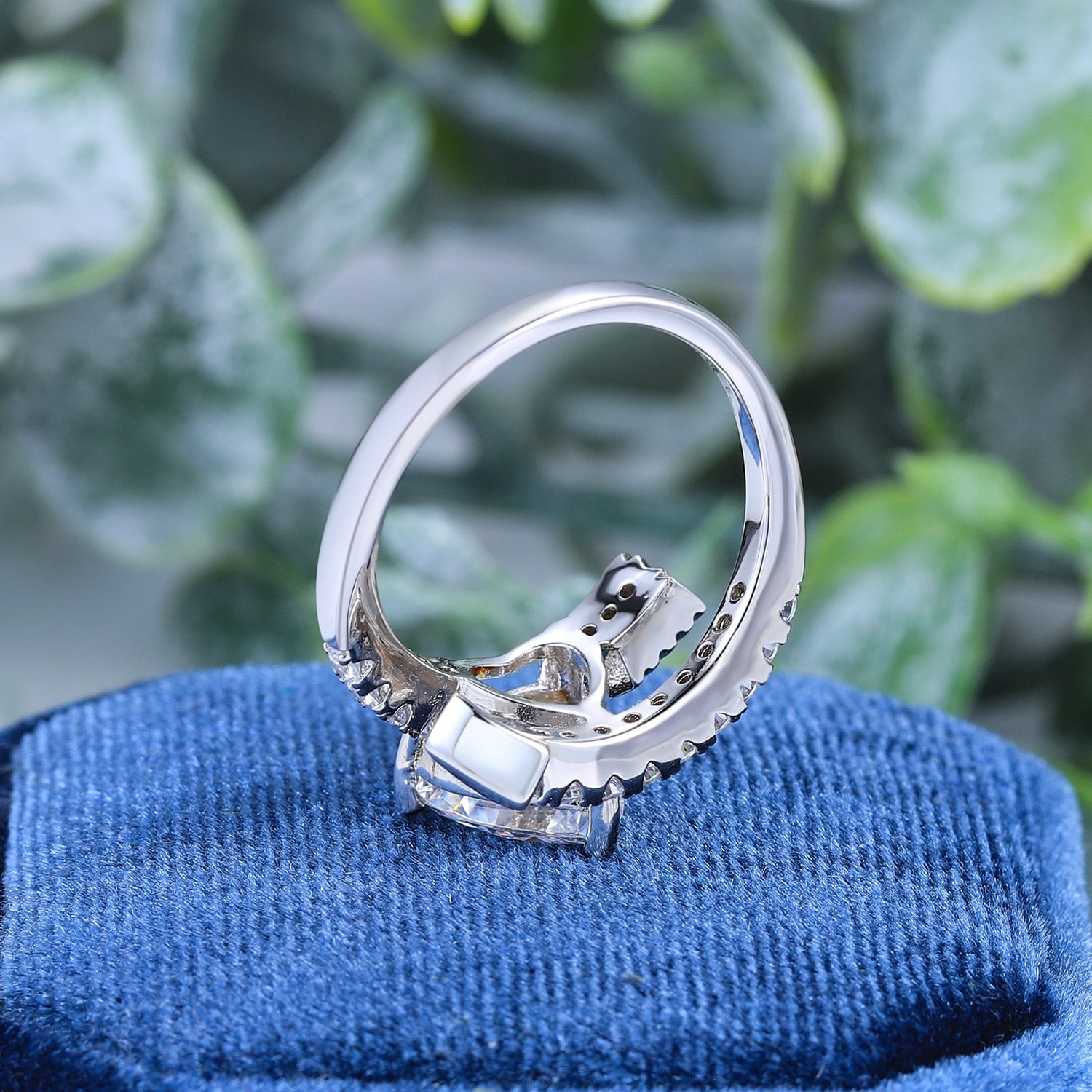 A silver wrap around bypass style ring resembling a pave studded arrow, set with a 4CT heart cut moissanite.