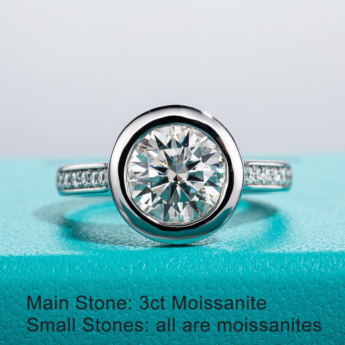 A 3CT moissanite, bezel set in a floating setting on a pave band. Wording "Main stone is moissanite and small stones are all moissanite."