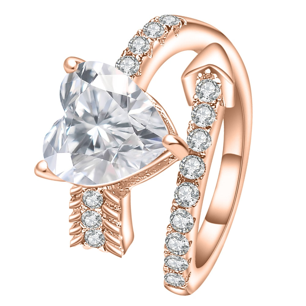 A rose gold wrap around bypass style ring resembling a pave studded arrow, set with a 4CT heart cut moissanite.