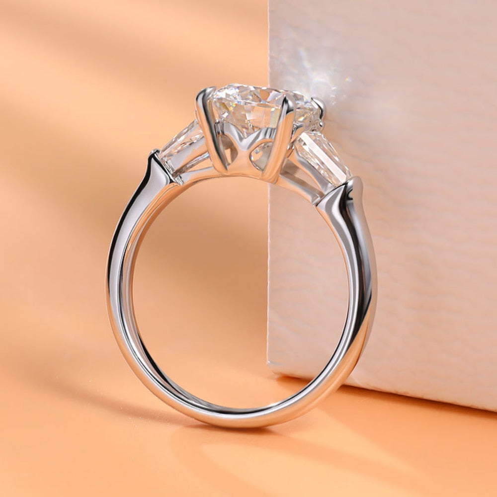 A silver round and trapezoid 3 stone engagement ring.