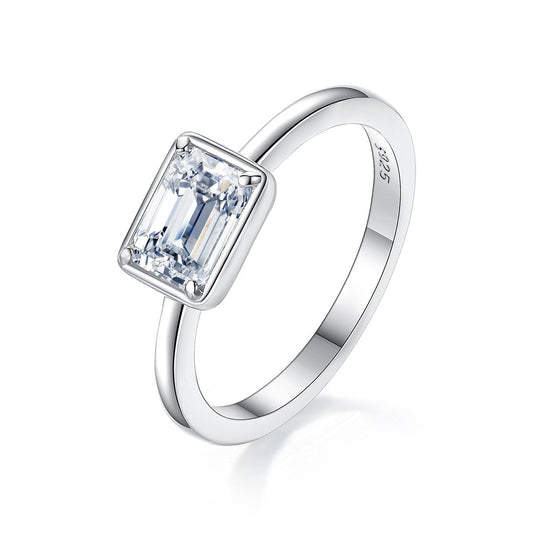 A silver emerald cut east to west bezel set engagement ring.