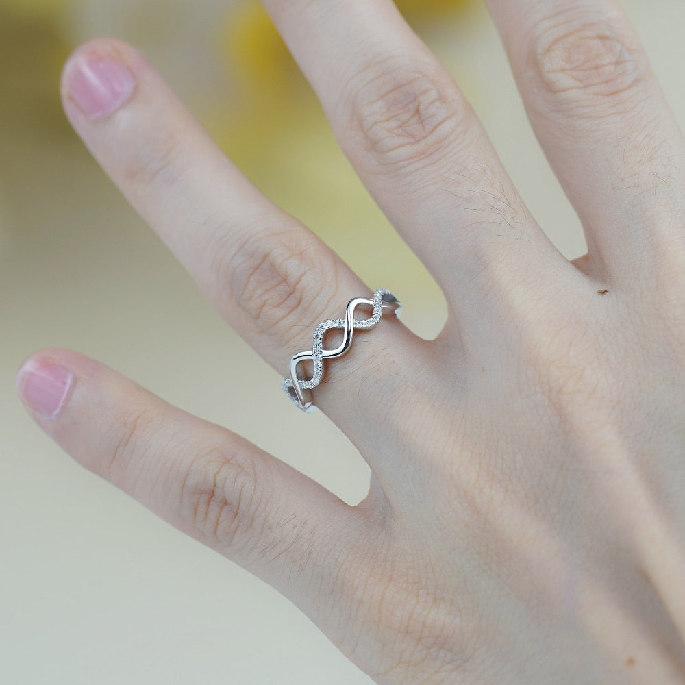 A hand wearing a silver half silver pave and half plain silver  twisted into a stackable ring.