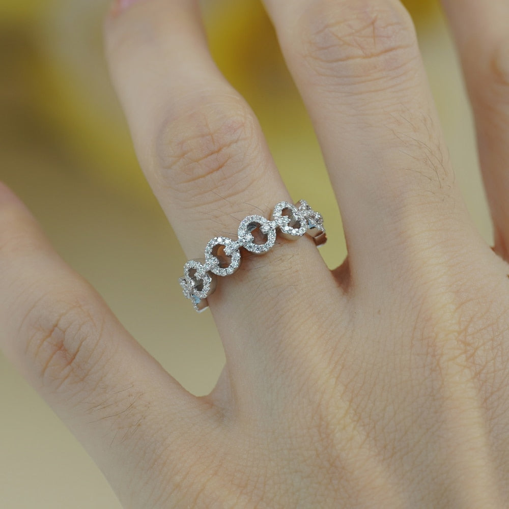 A hand wearing a silver round chain link style ring set with moissanites.