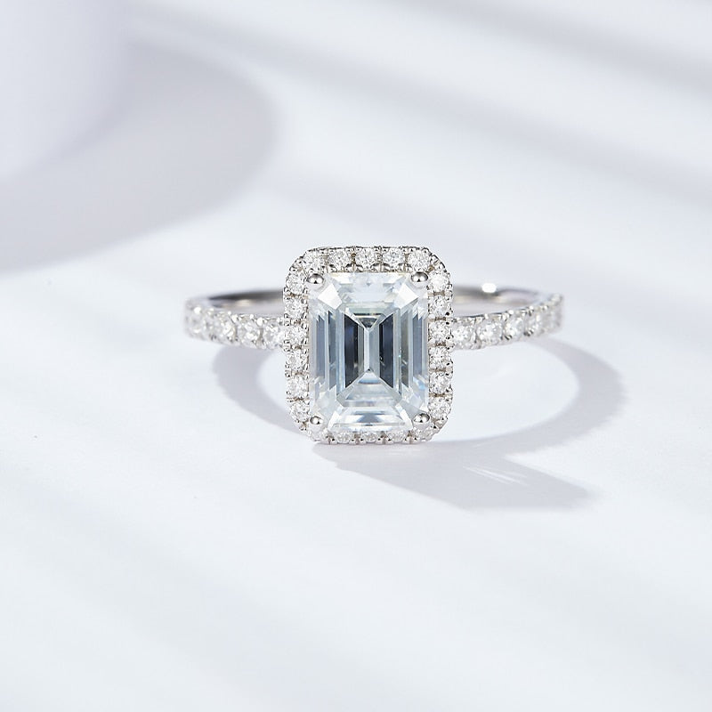 A silver emerald cut moissanite halo engagement ring.
