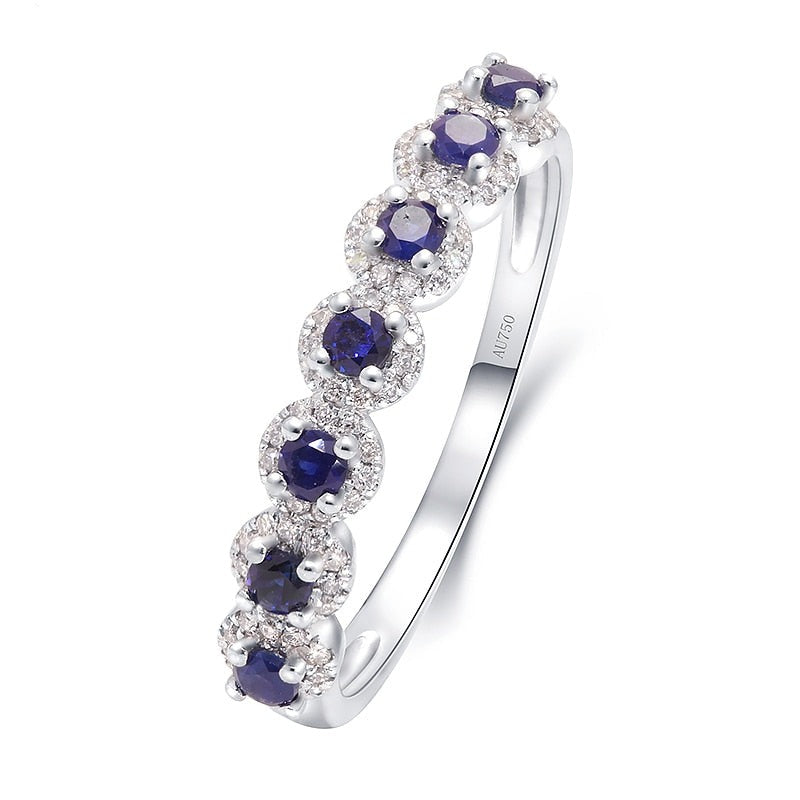 A silver wedding ring with 7 small lab grown sapphire encircled with moissanite halos.