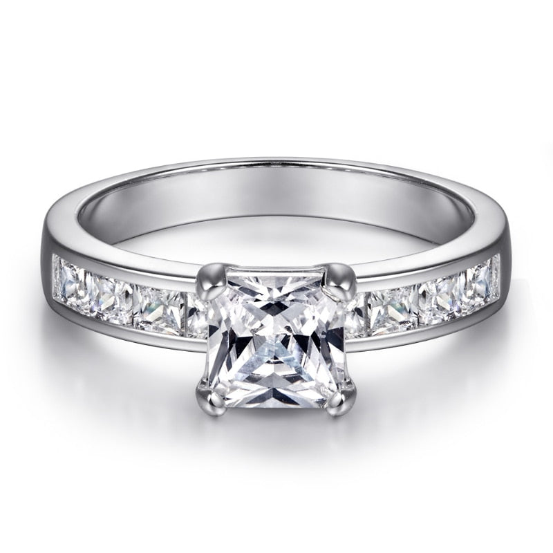 A silver ring set with small princess cut zircons, channel set in the shank and a princess cut moissanite set as the main gem. 