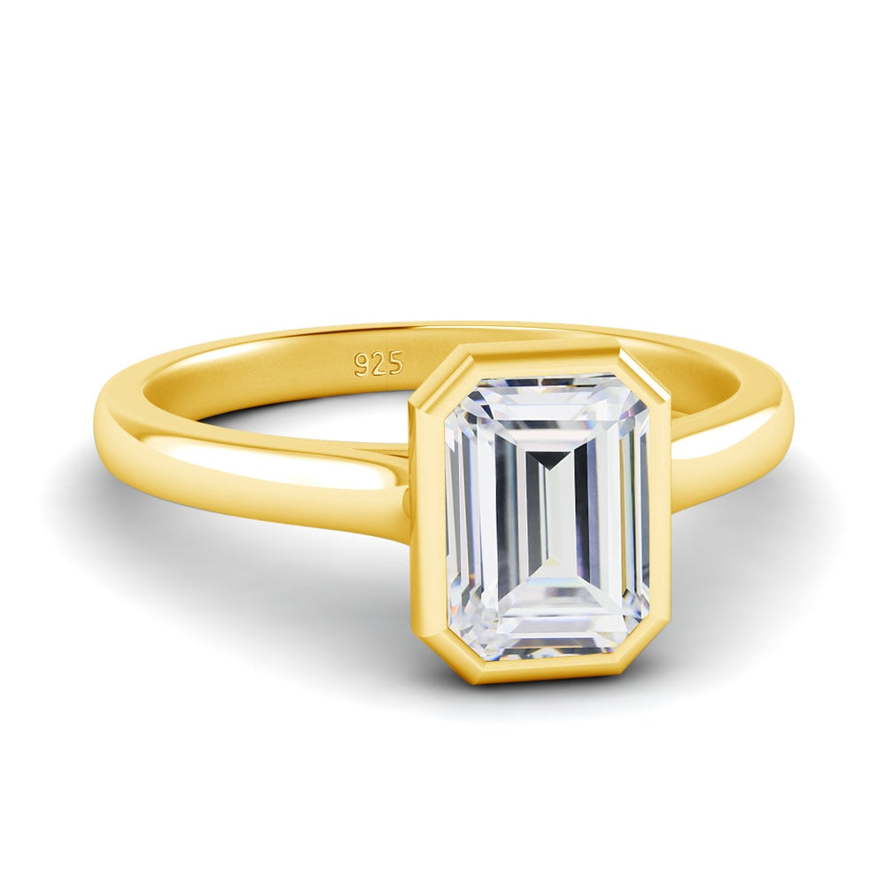 A gold bezel set emerald cut moissanite ring.