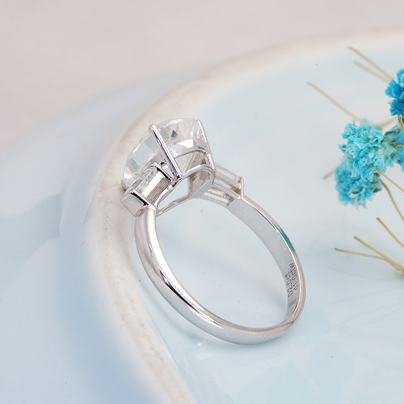 A silver 3 stone ring set with a 2CT tear drop moissanite set between two east to west set moissanite baguettes.