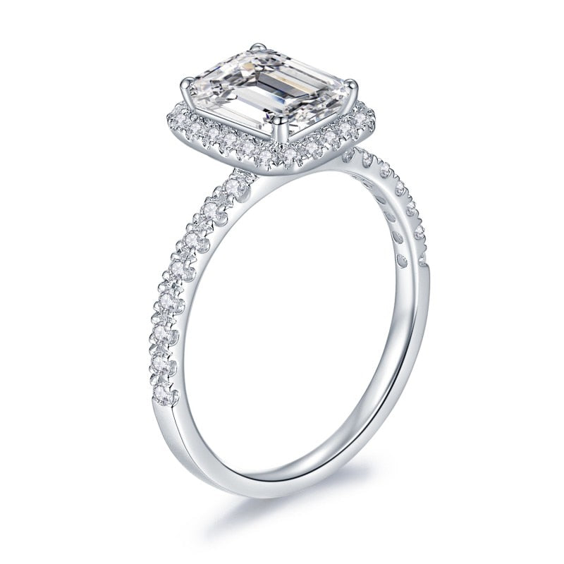 A silver emerald cut moissanite halo engagement ring.