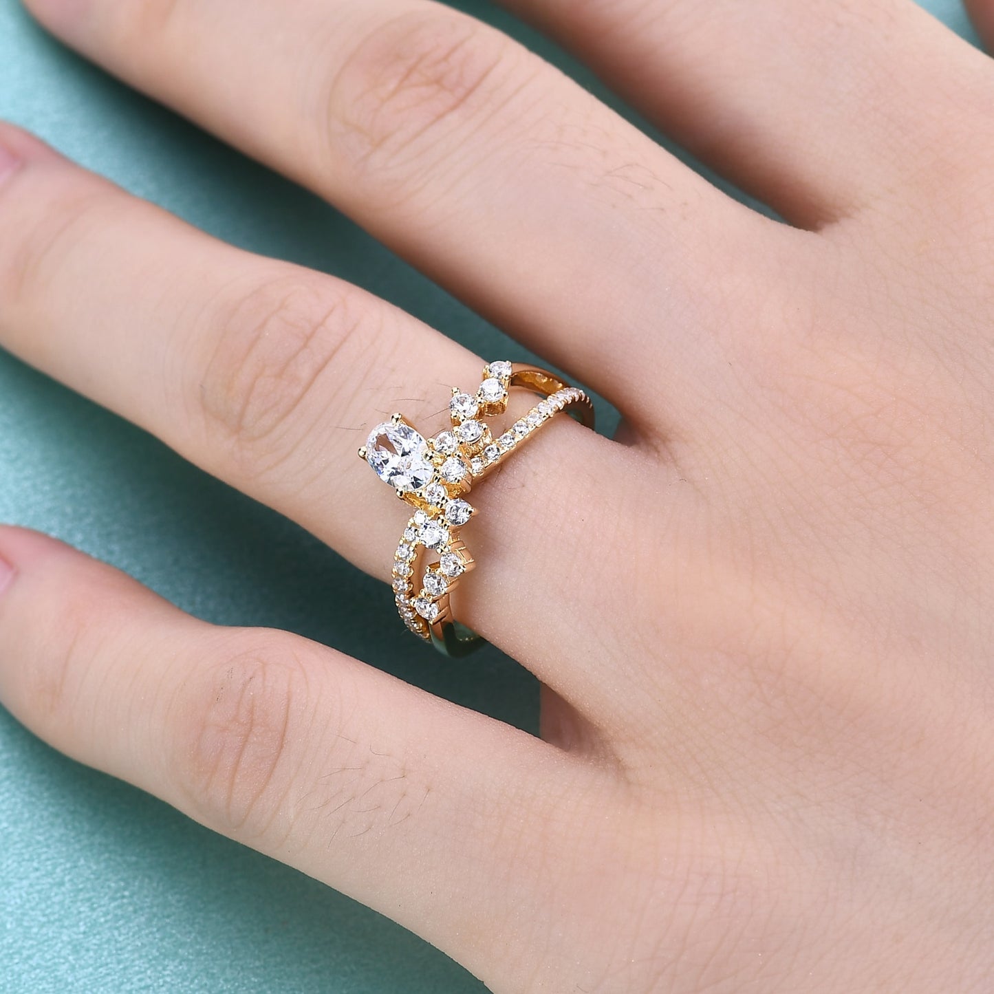 A hand wearing a gold asymmetrical twisted pave band ring with random sized moissanites and set with a oval moissanite.