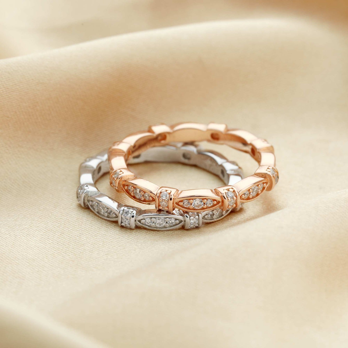 One silver and one rose gold ribbon scalloped style ring set with clear small gems.