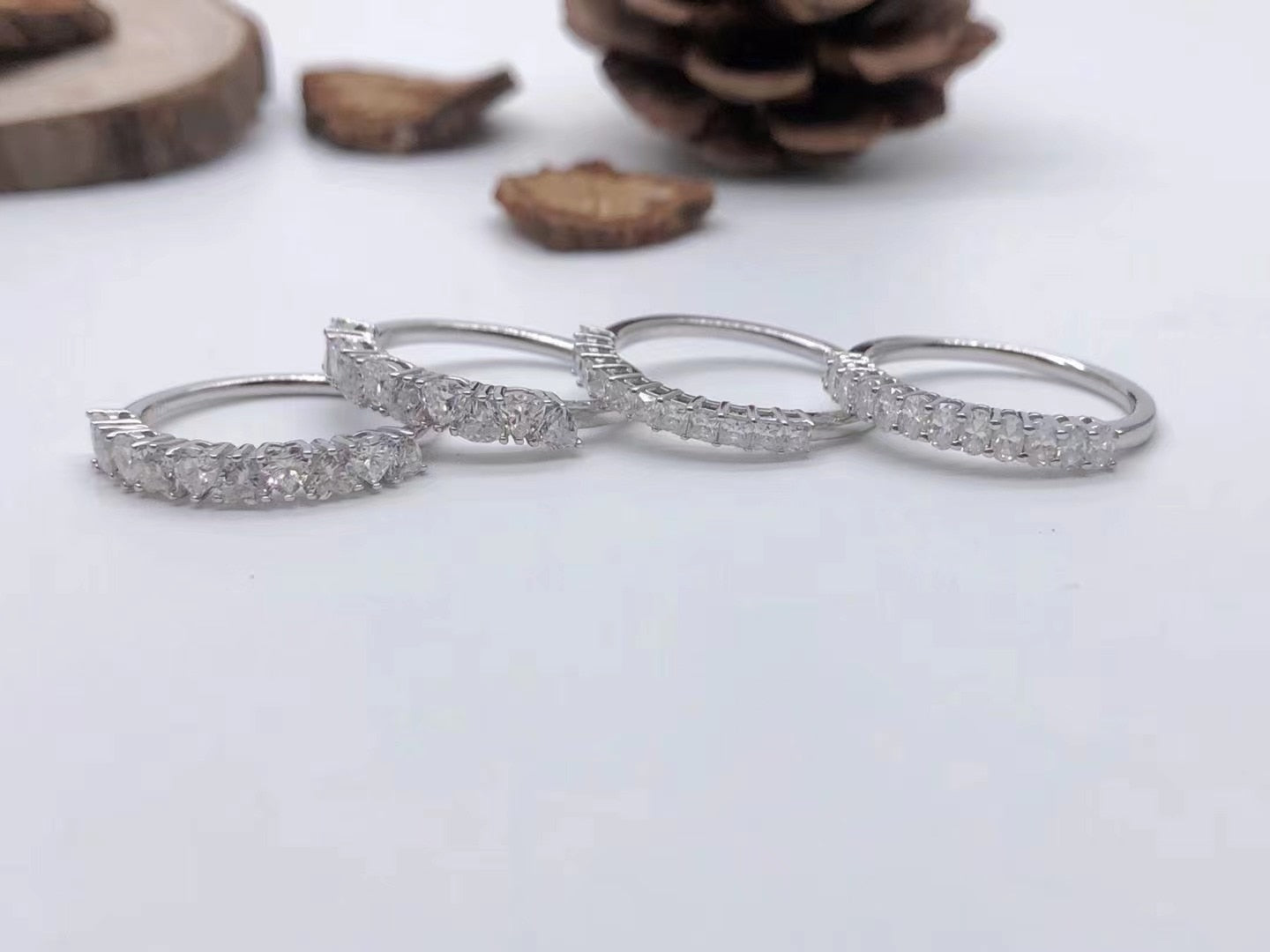 Four half eternity rings with various cuts of moissanite laying on a table.