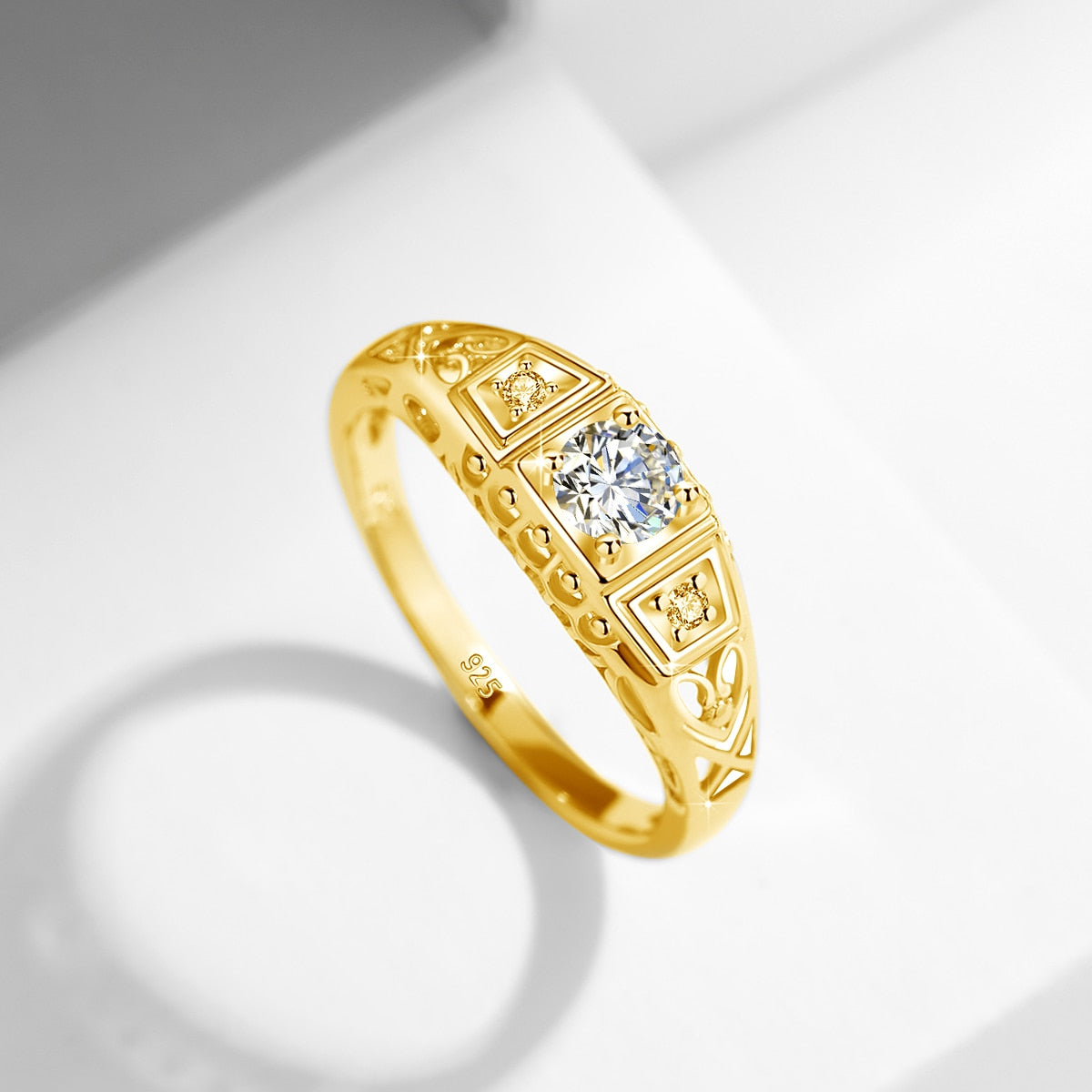A gold Edwardian style vintage filigree engagement ring with a larger stone surrounded by two smaller side stones.