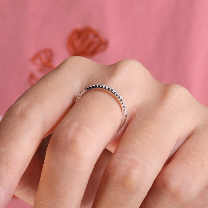 A hand wearing a silver half eternity ring.