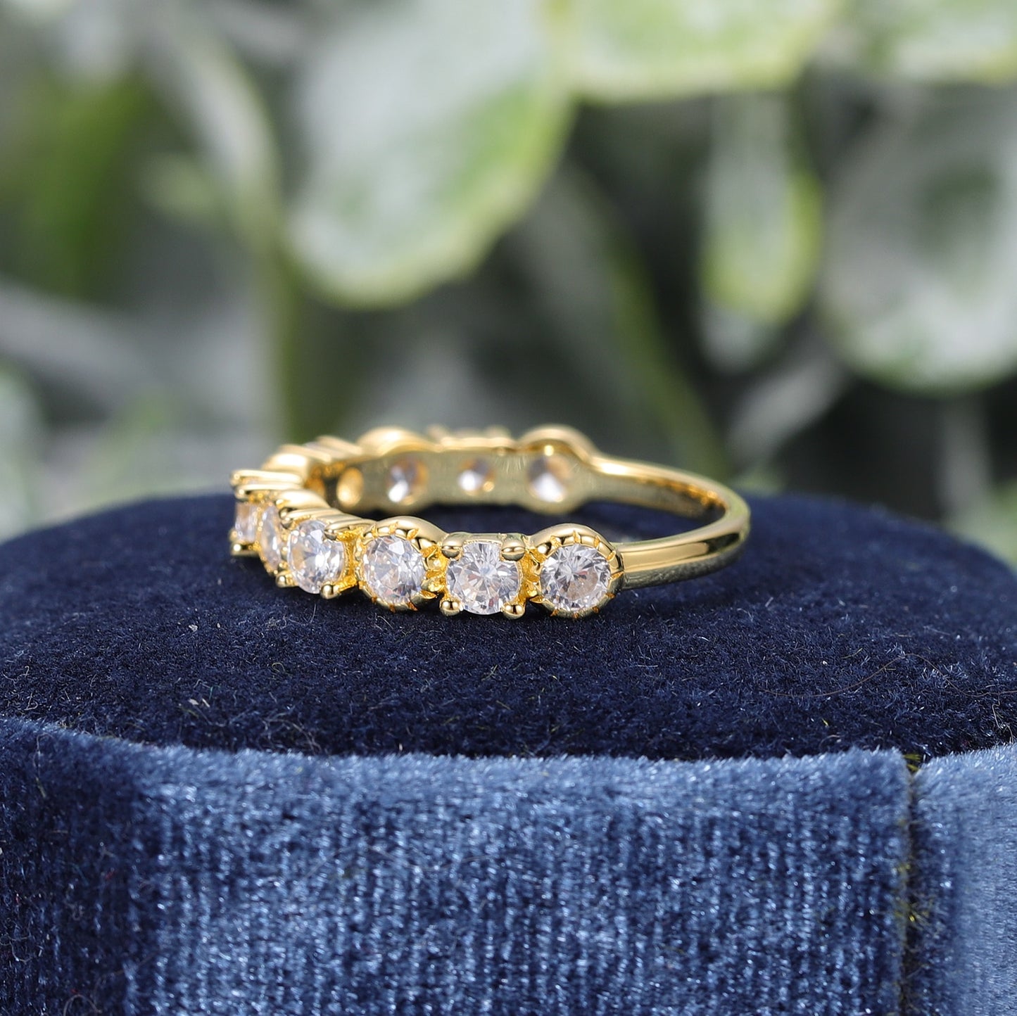 A gold wedding ring set with round moissanites, alternating between prong and bezel set.