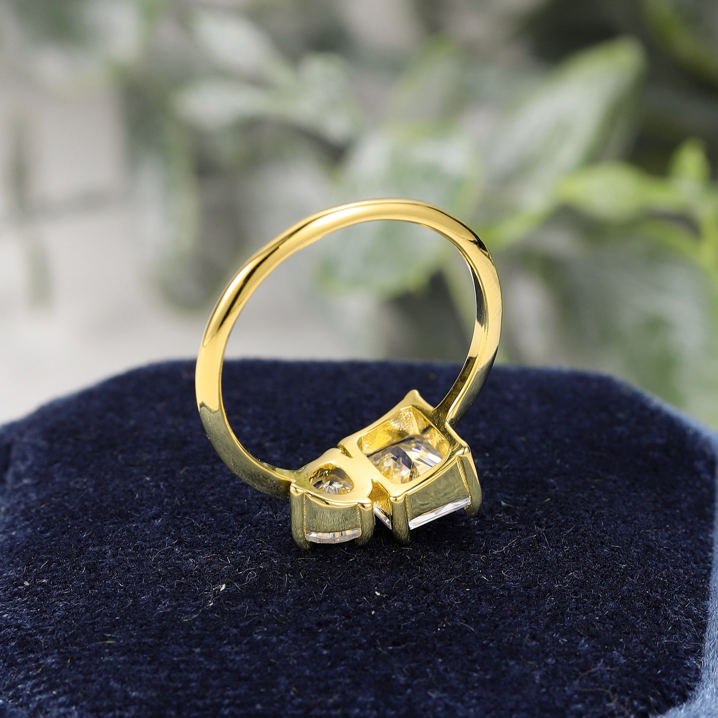 A gold Toi et Moi ring with a emerald cut moissanite and a tear drop moissanite.