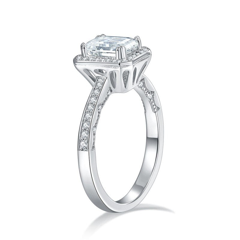 A silver halo ring set with an emerald cut moissanite.