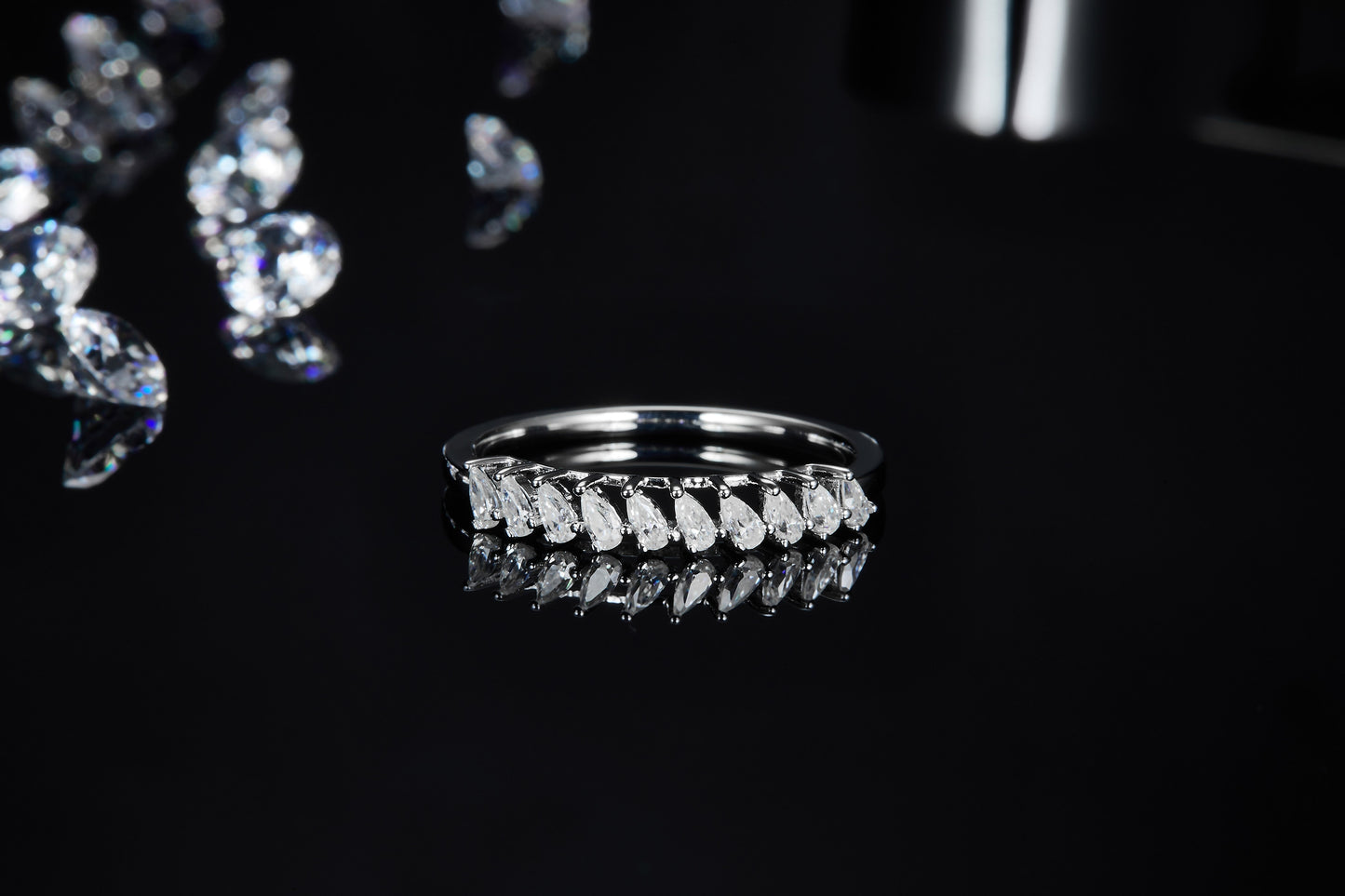 A silver wedding ring set with several vertical pear cut clear gems.