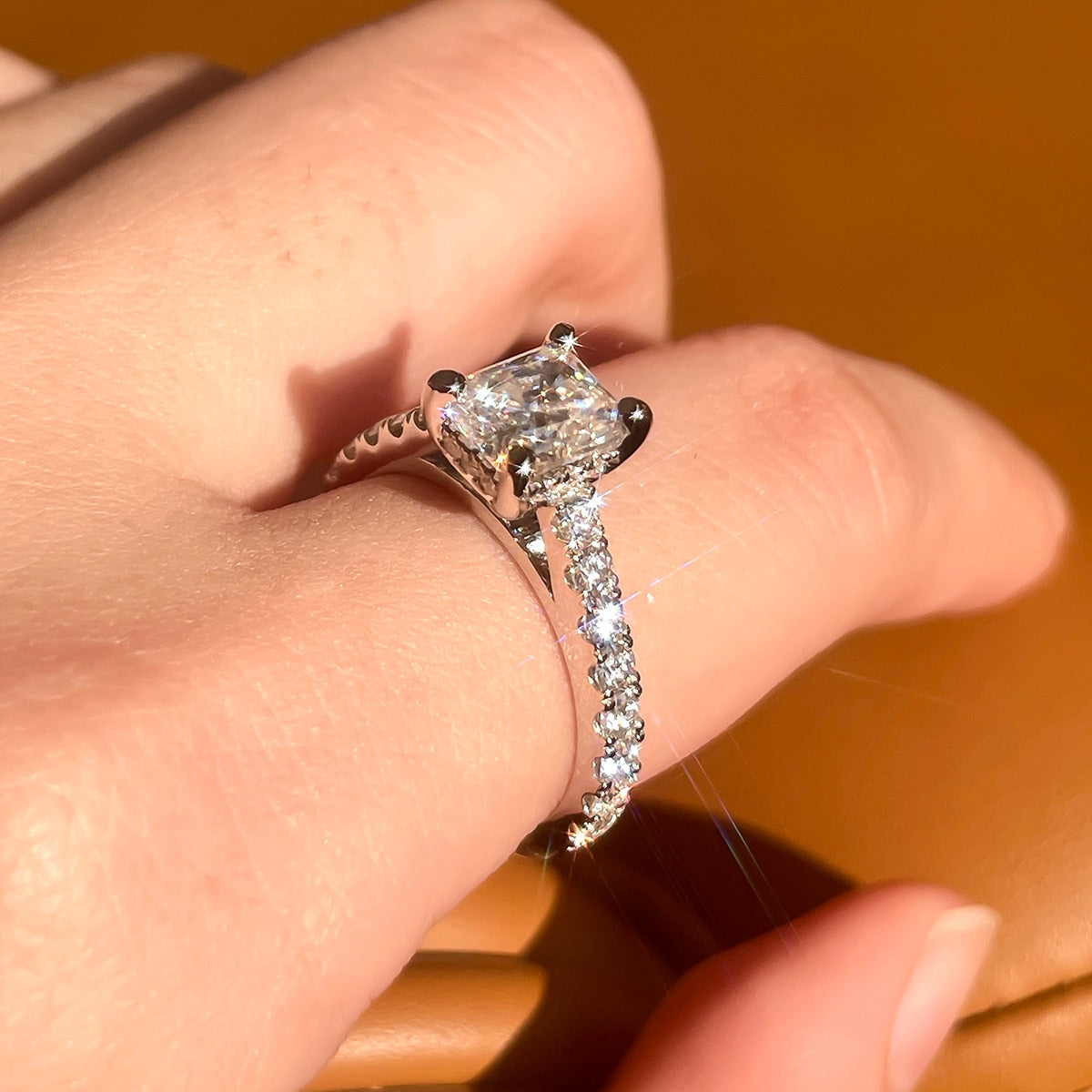 Hand wearing a sterling silver radiant cut moissanite set in a moissanite hidden halo and pave band.
