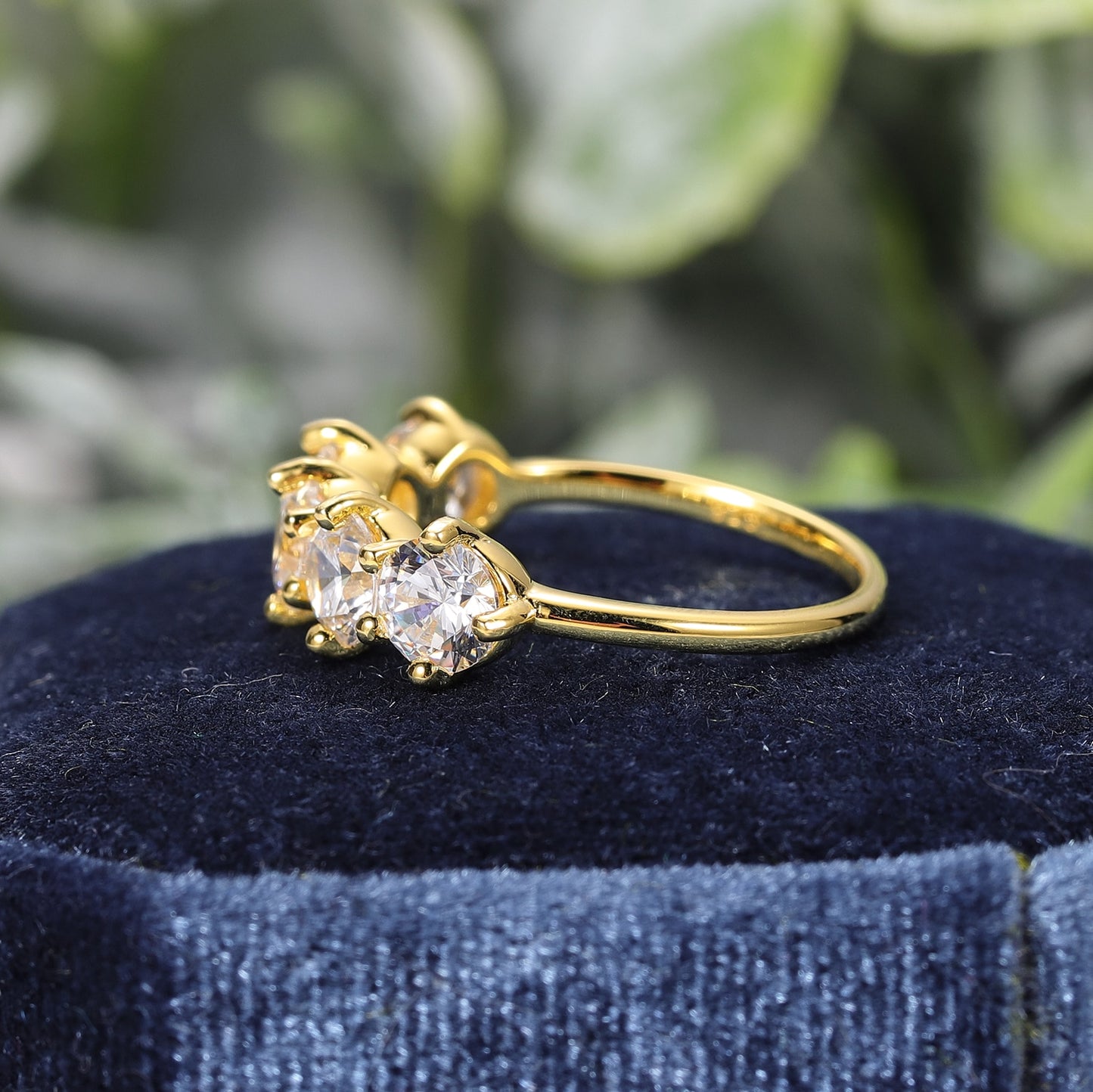 A gold ring with 5 half carat round moissanites set horizontally on the band.