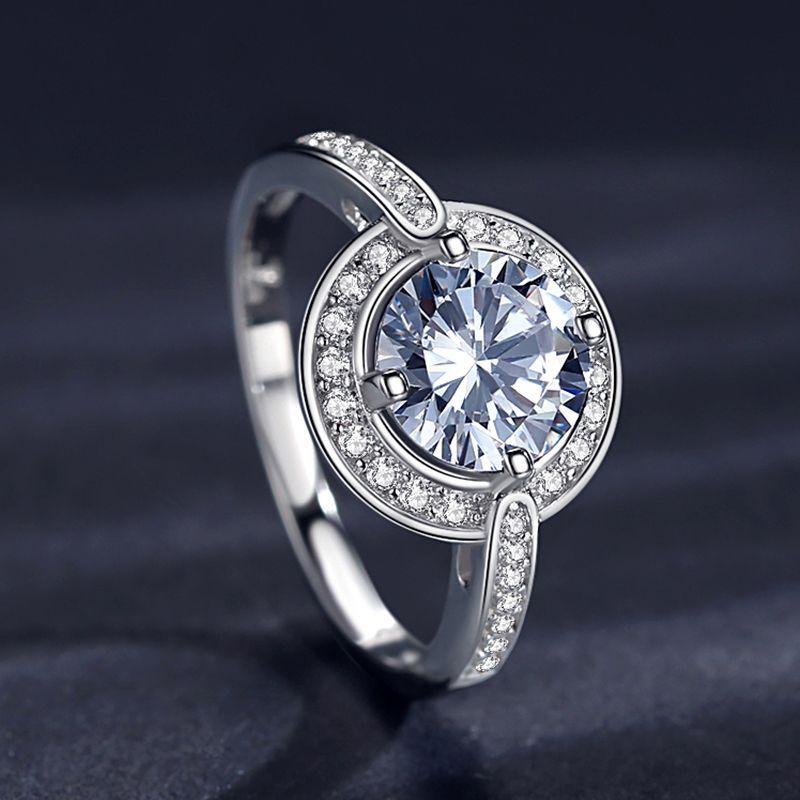 A silver halo ring set with a large moissanite in a circle of channel style set zircons.
