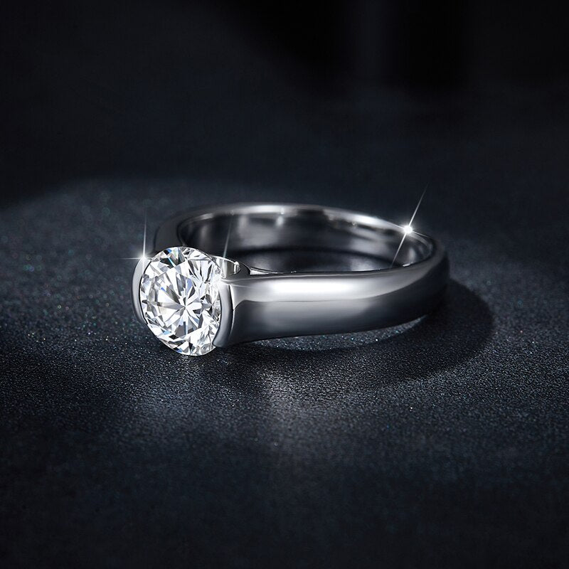 A silver bezel tension set round moissanite on a thick shank.