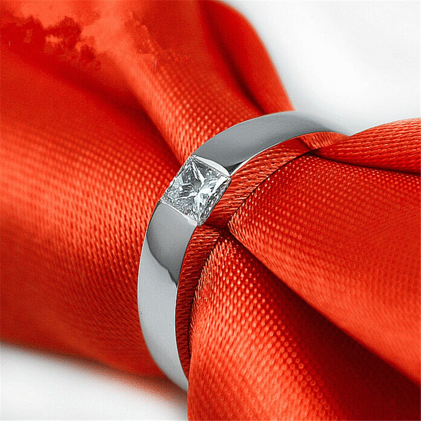 A silver solid band tension set with a princess cut moissanite.