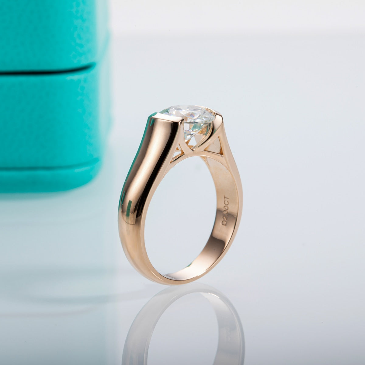 A rose gold plated round cut moissanite tension set in a floating half bezel setting.