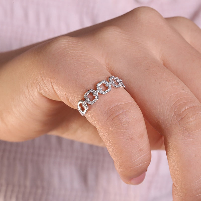 A hand wearing a silver gem encrusted chain link style ring.