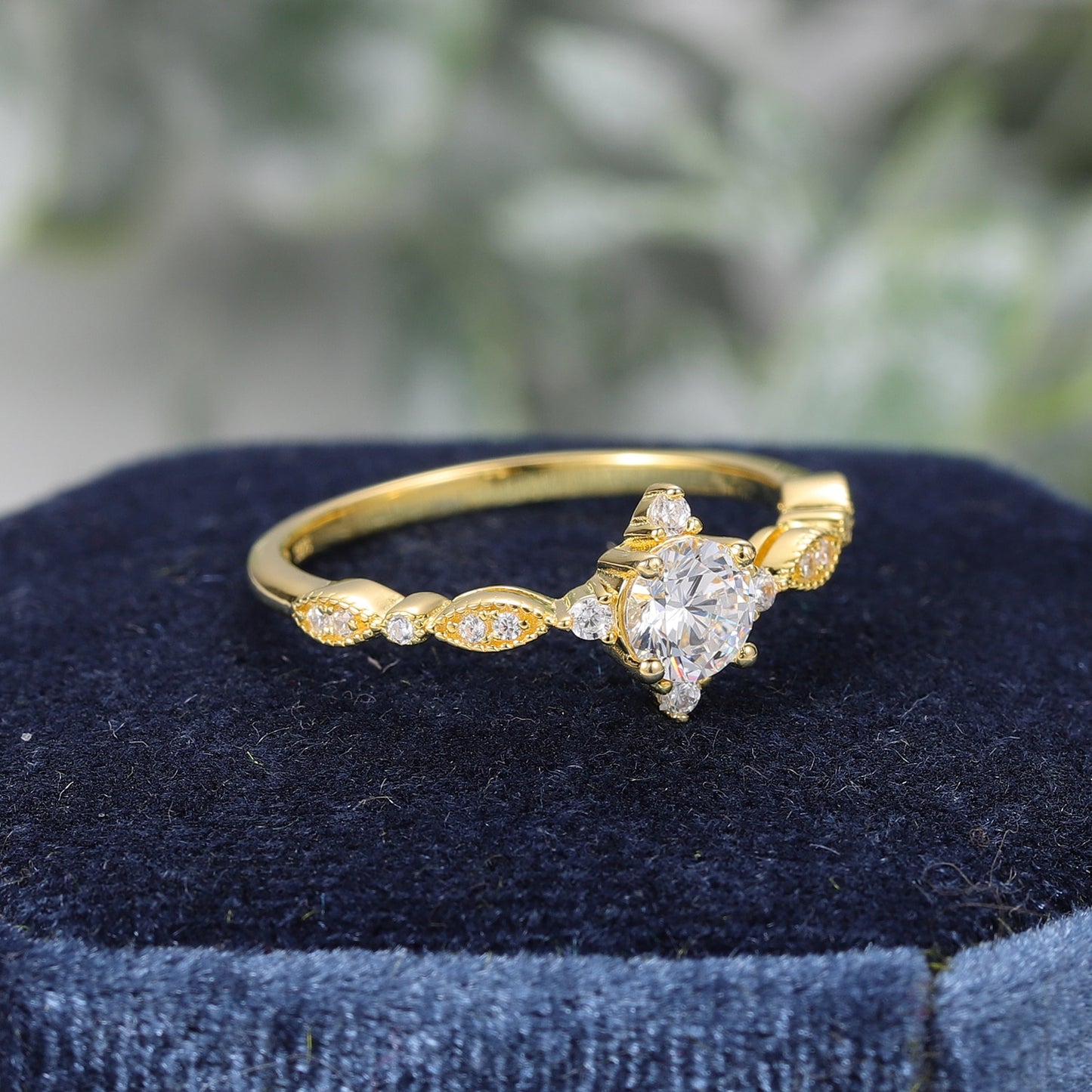 A gold vintage inspired engagement ring set with a round moissanite and 4 small zircons on all four sides.