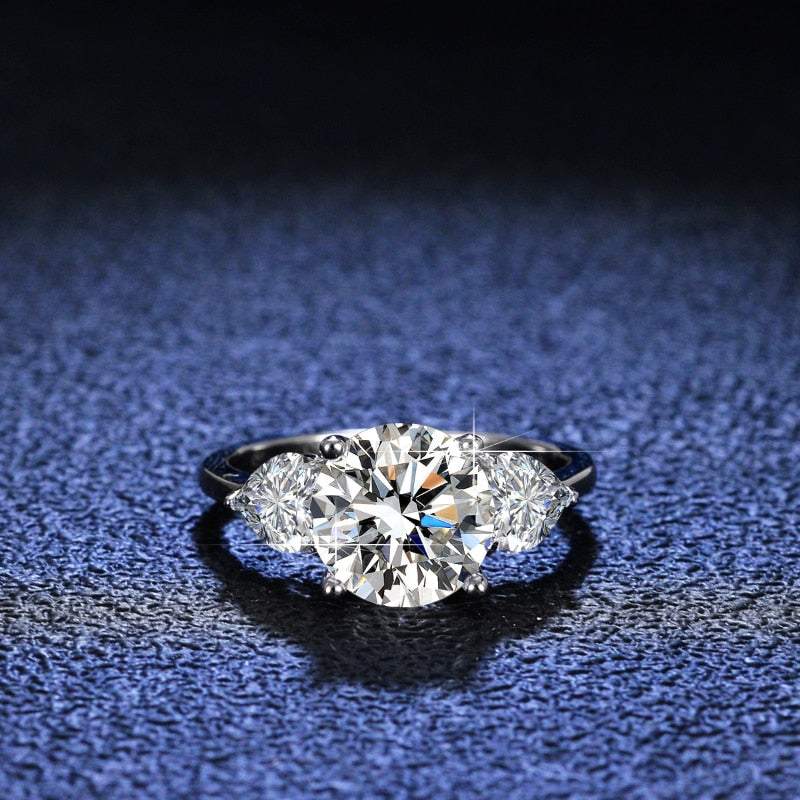 A silver 3 stone ring set with a round cut moissanite and two heart cut zircons.