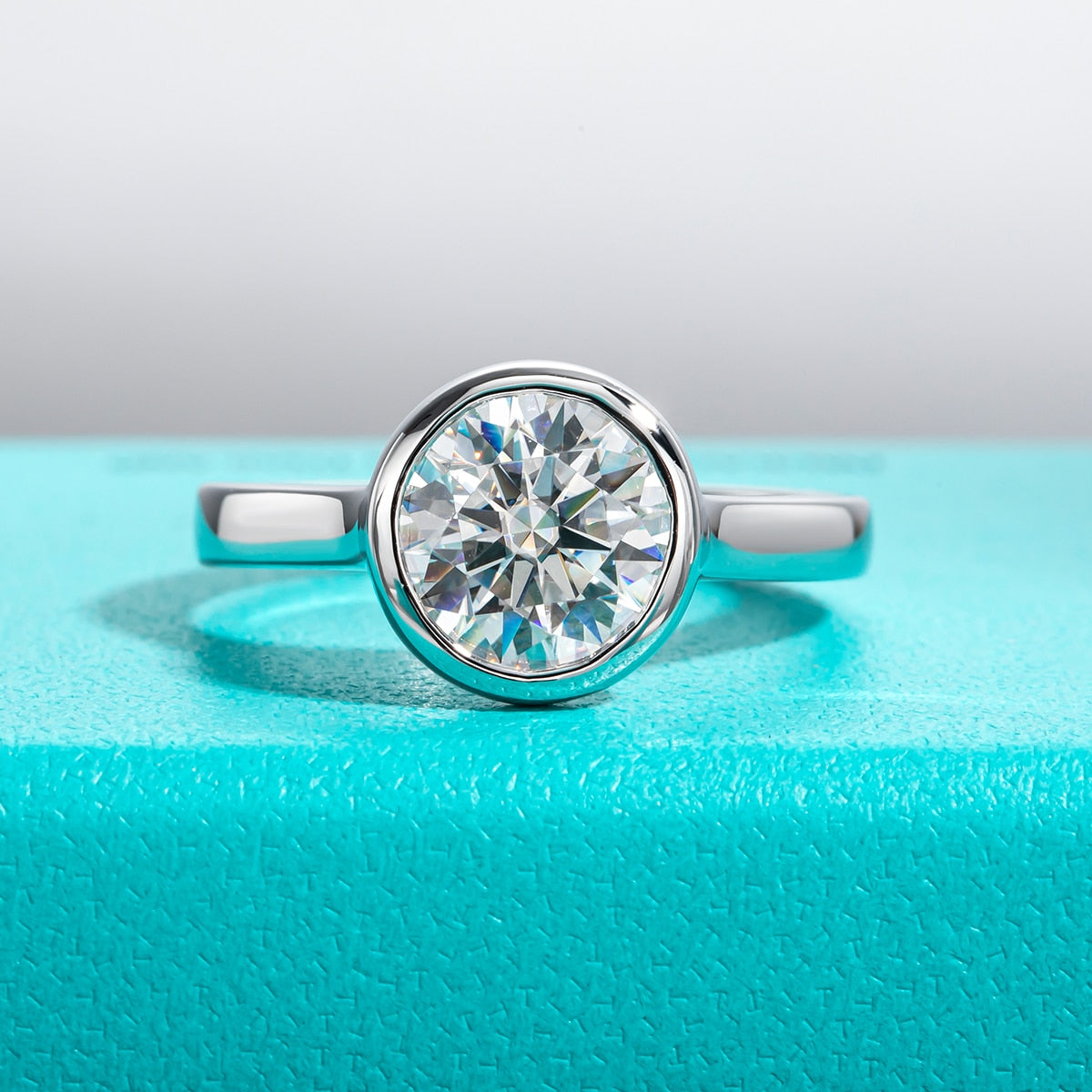 A sterling silver engagement ring with a 3CT round cut moissanite in a bezel setting.