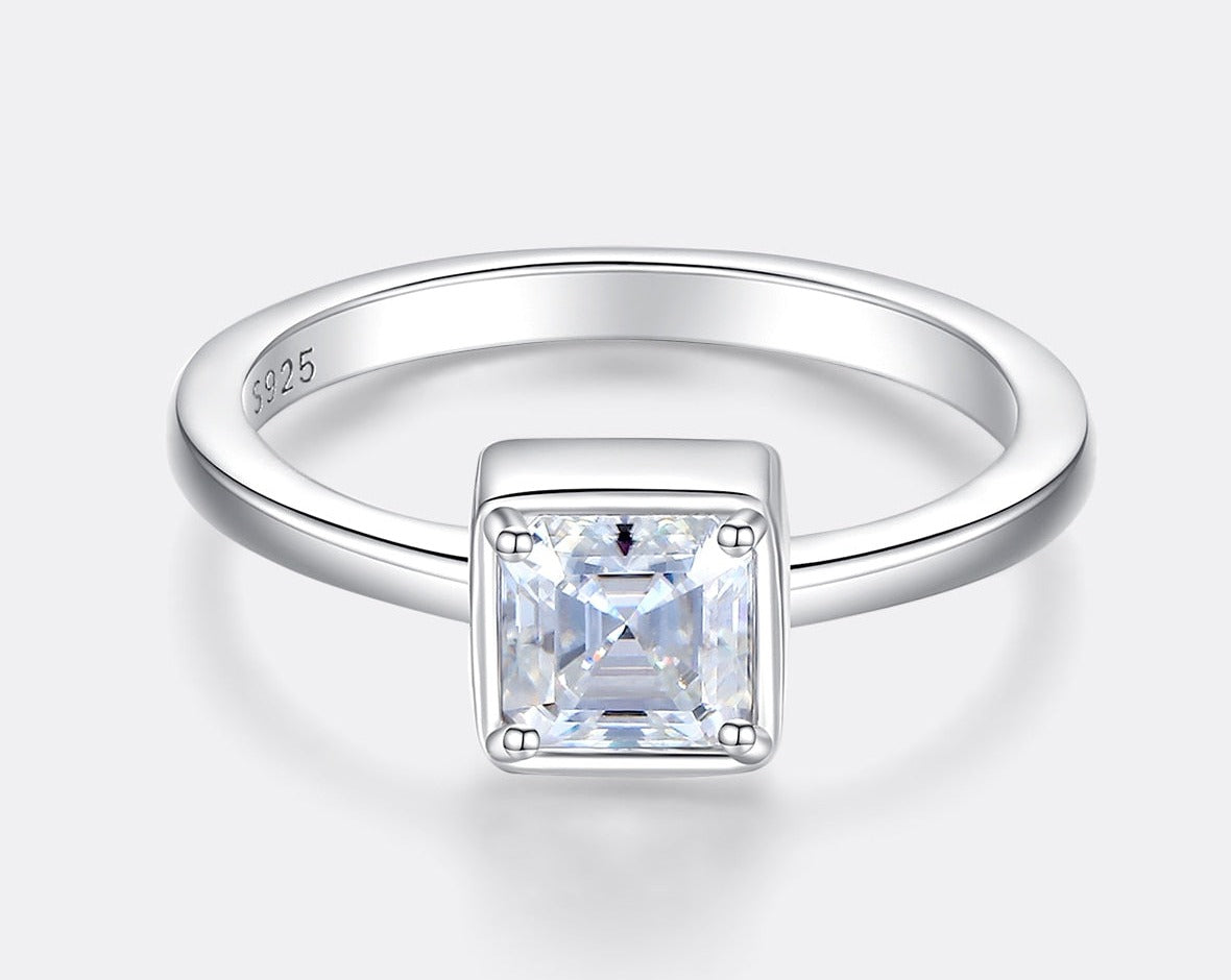 A silver Asscher cut bezel set engagement ring.